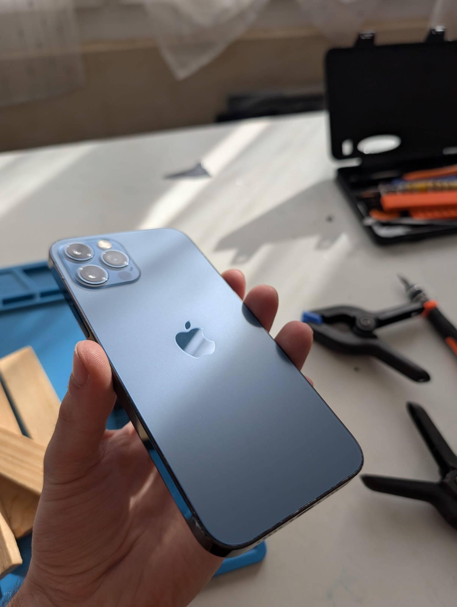 iPhone réparé tenu en main dans l'atelier